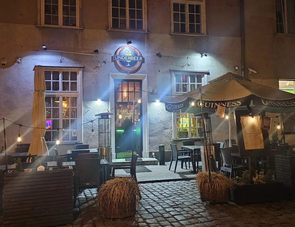 Kamienica pubu wieczorem, oświetlone stoliki na ulicy