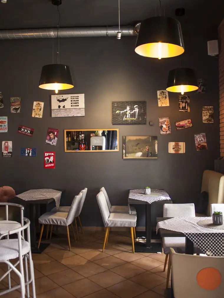 Sala z ciemnymi stolikami i lampami